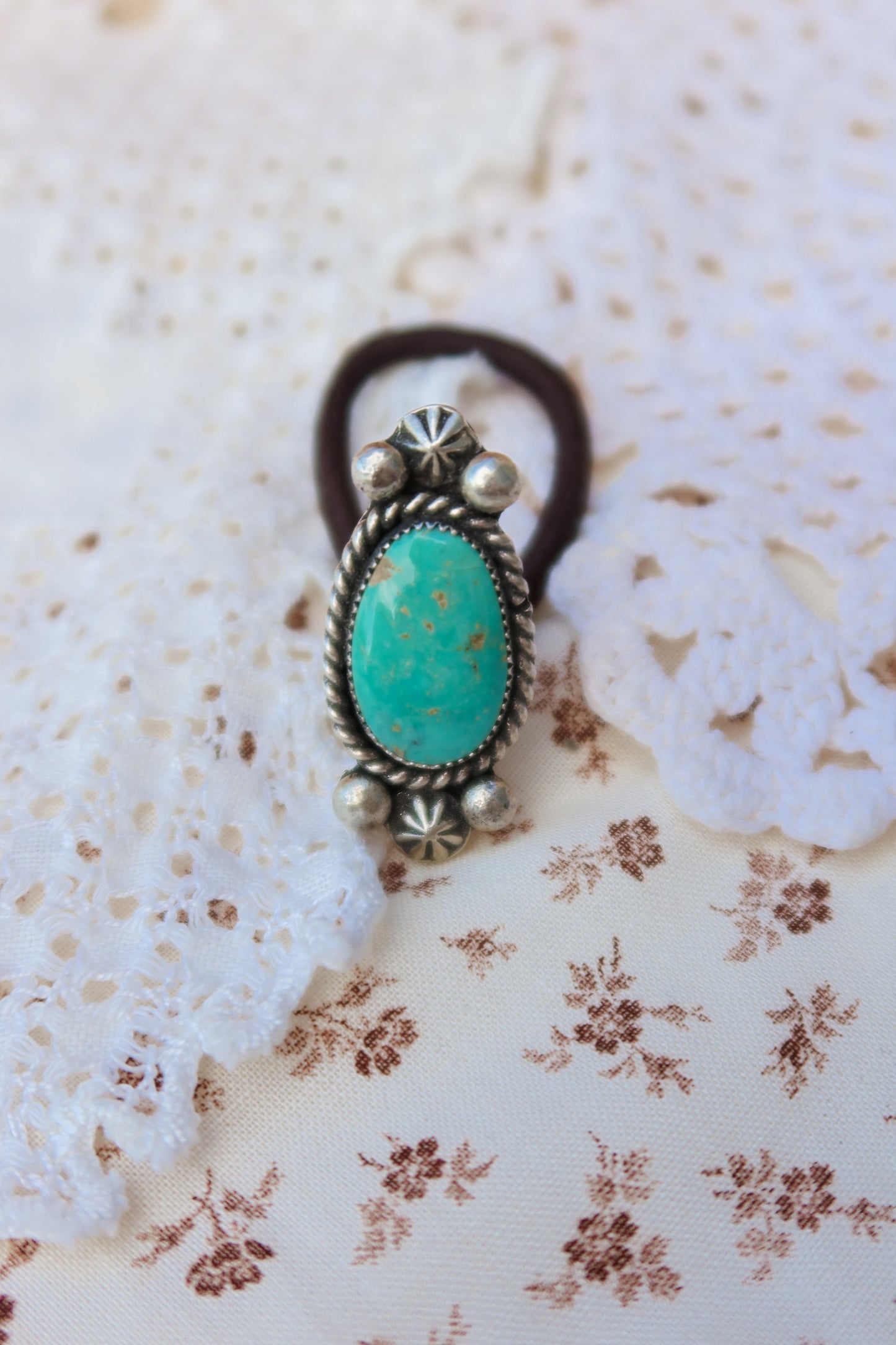 Elevate your everyday style with this stunning hair tie featuring genuine Sonoran turquoise with sterling silver ornaments. Available in three versatile options to match your look: Black, Brown, or blonde. Perfect for securing your hair while making a statement. 