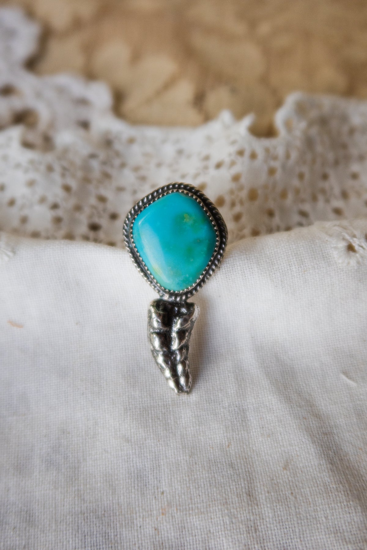 This one-of-a-kind Sterling Silver Turquoise Rattler Ring is handcrafted in the heart of South Texas. This whimsical beauty features a striking double ring shank design that wraps around your finger like a coiled serpent, crowned with genuine Kingman turquoise that captures the wild spirit of the south Texas Terrain. Each piece is uniquely crafted, making it a treasure that's as individual as you are.&nbsp;