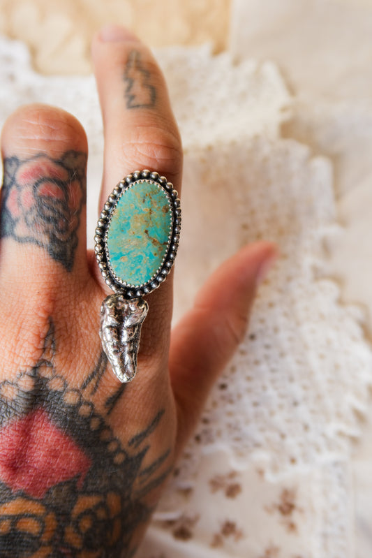 This one-of-a-kind Sterling Silver Turquoise Rattler Ring is handcrafted in the heart of South Texas. This whimsical beauty features a striking double ring shank design that wraps around your finger like a coiled serpent, crowned with genuine Kingman turquoise that captures the wild spirit of the south Texas Terrain. Each piece is uniquely crafted, making it a treasure that's as individual as you are.&nbsp;