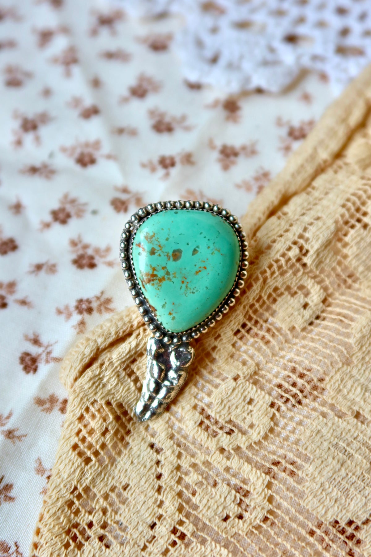 This one-of-a-kind Sterling Silver Turquoise Rattler Ring is handcrafted in the heart of South Texas. This whimsical beauty features a striking double ring shank design that wraps around your finger like a coiled serpent, crowned with genuine Kingman turquoise that captures the wild spirit of the south Texas Terrain. Each piece is uniquely crafted, making it a treasure that's as individual as you are.&nbsp;