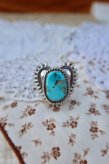 Handcrafted sterling silver heartbreaker ring featuring a striking blue gem turquoise stone set in a sand-cast design. This size 5 3/4 ring showcases the natural beauty of turquoise with its rich blue hues and organic texture, created using traditional sand casting techniques that give each piece a unique character. Perfect for everyday wear or special occasions.