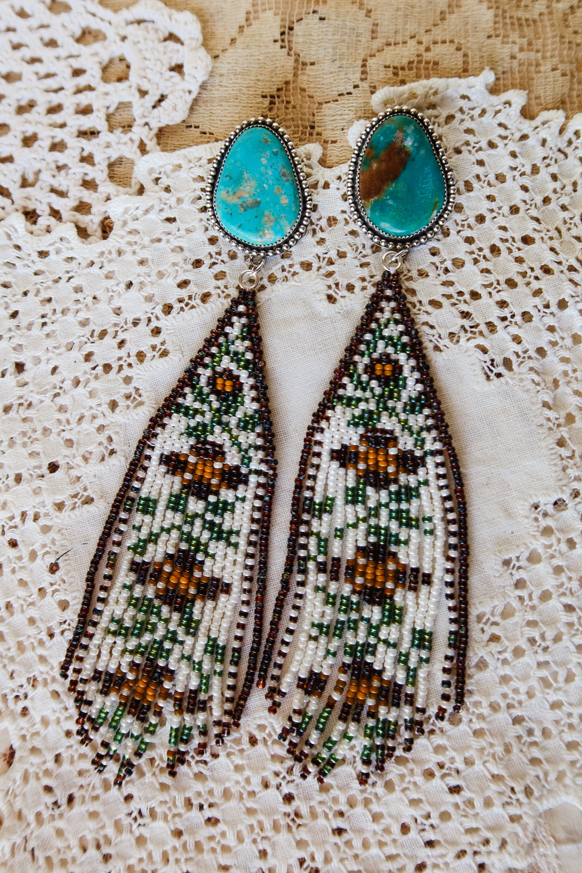 Bloom where you're beaded! These whimsical Sterling Silver and Turquoise Beaded Floral Earrings bring a touch of Southwestern charm to your everyday style. Each pair is meticulously hand-beaded with vibrant turquoise stones, creating delicate floral designs that dance with every movement. Handcrafted with love in South Texas, these earrings are a celebration of uniqueness and eccentric style. Perfect for adding a pop of color and personality to any outfit.