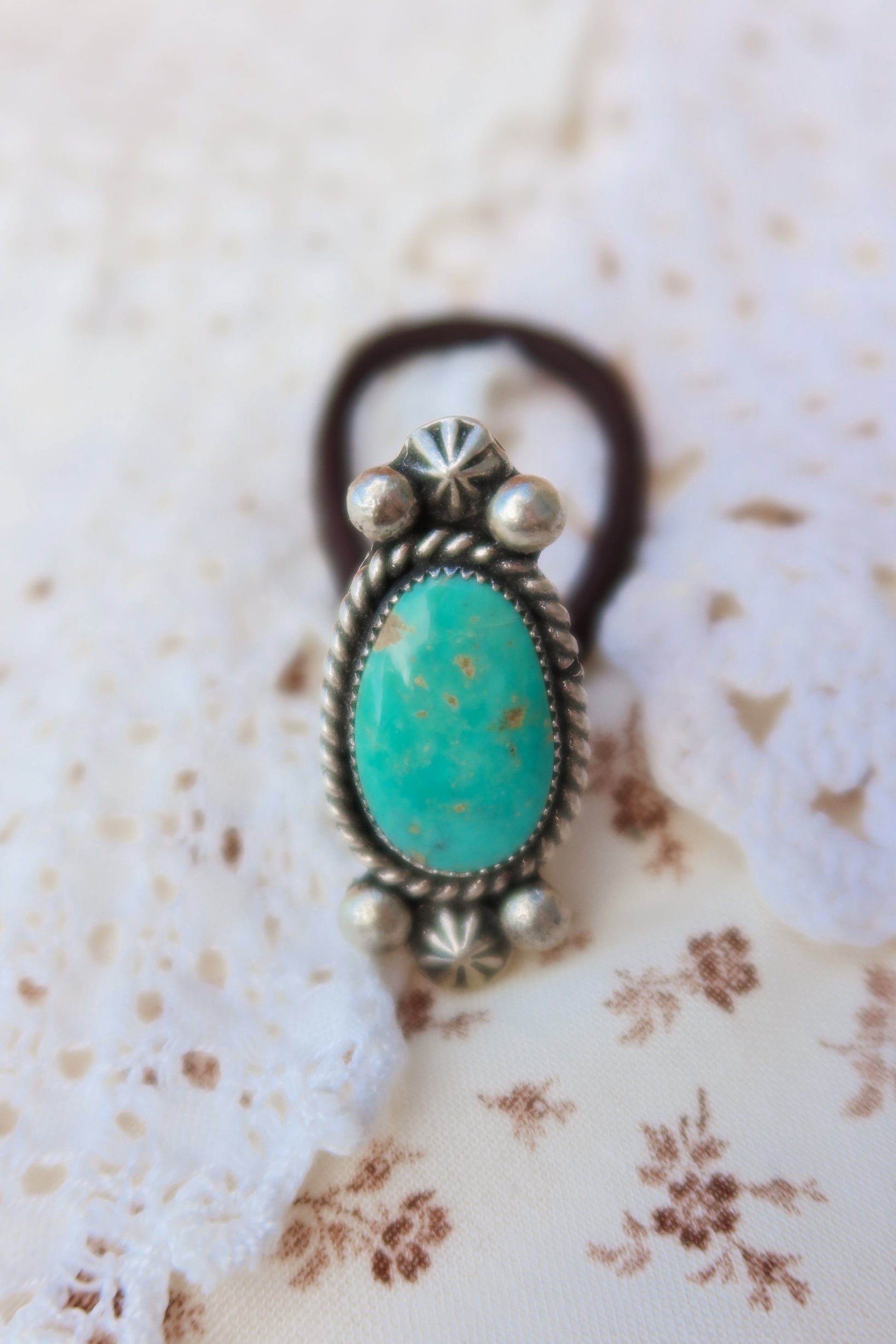 Elevate your everyday style with this stunning hair tie featuring genuine Sonoran turquoise with sterling silver ornaments. Available in three versatile options to match your look: Black, Brown, or blonde. Perfect for securing your hair while making a statement.&nbsp;