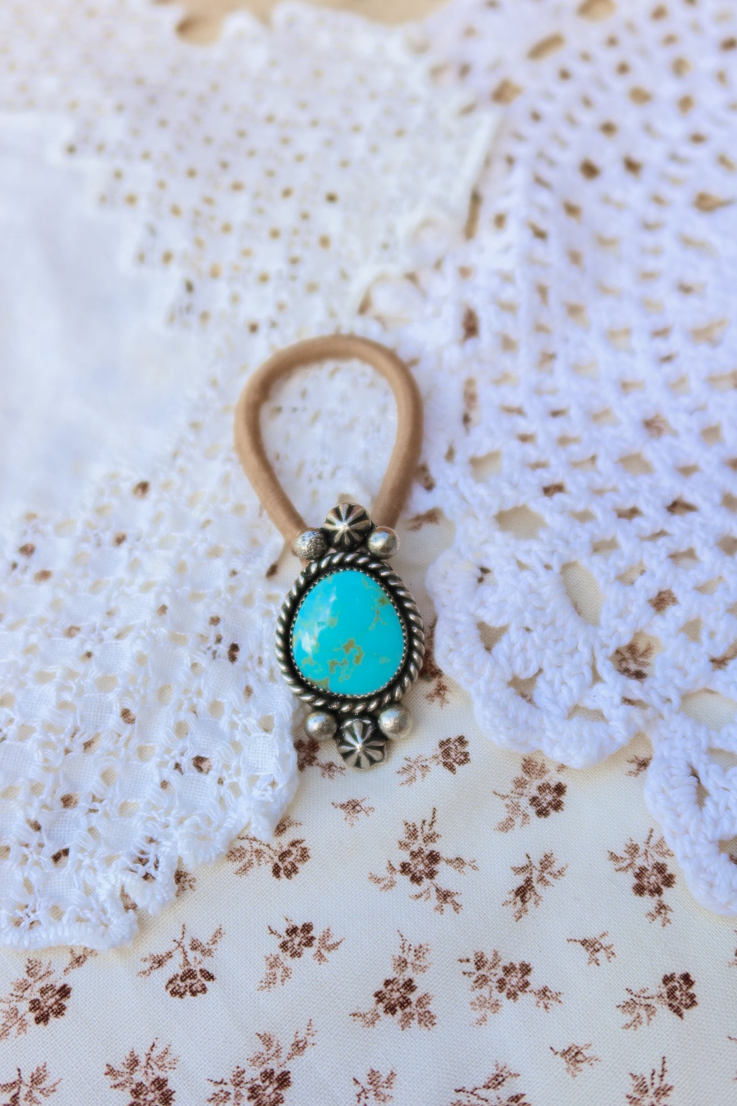 Elevate your everyday style with this stunning hair tie featuring genuine Sonoran turquoise with sterling silver ornaments. Available in three versatile options to match your look: Black, Brown, or blonde. Perfect for securing your hair while making a statement.&nbsp;