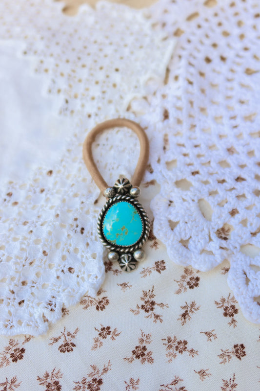 Elevate your everyday style with this stunning hair tie featuring genuine Sonoran turquoise with sterling silver ornaments. Available in three versatile options to match your look: Black, Brown, or blonde. Perfect for securing your hair while making a statement.&nbsp;