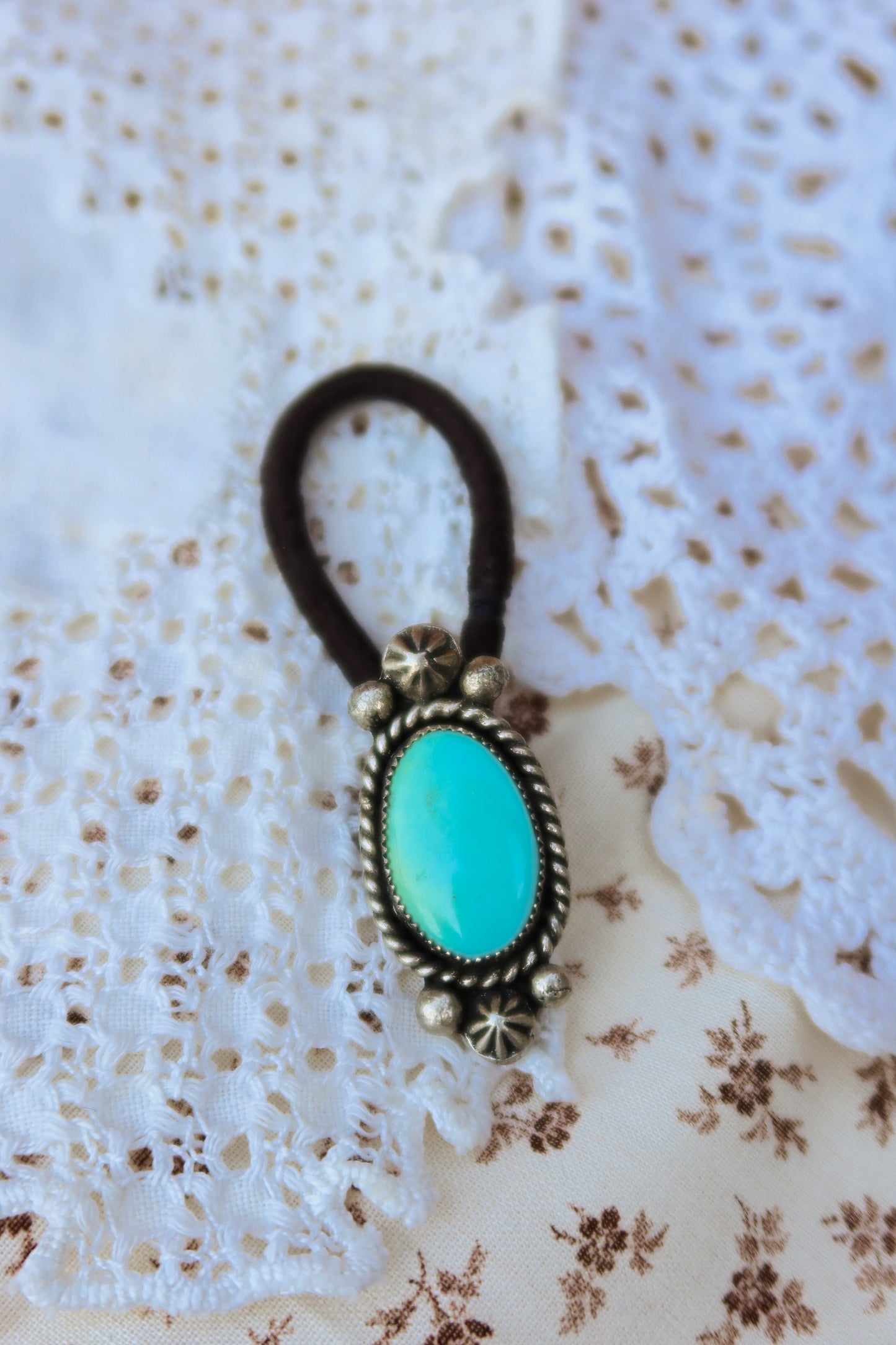 Elevate your everyday style with this stunning hair tie featuring genuine Sonoran turquoise with sterling silver ornaments. Available in three versatile options to match your look: Black, Brown, or blonde. Perfect for securing your hair while making a statement.&nbsp;