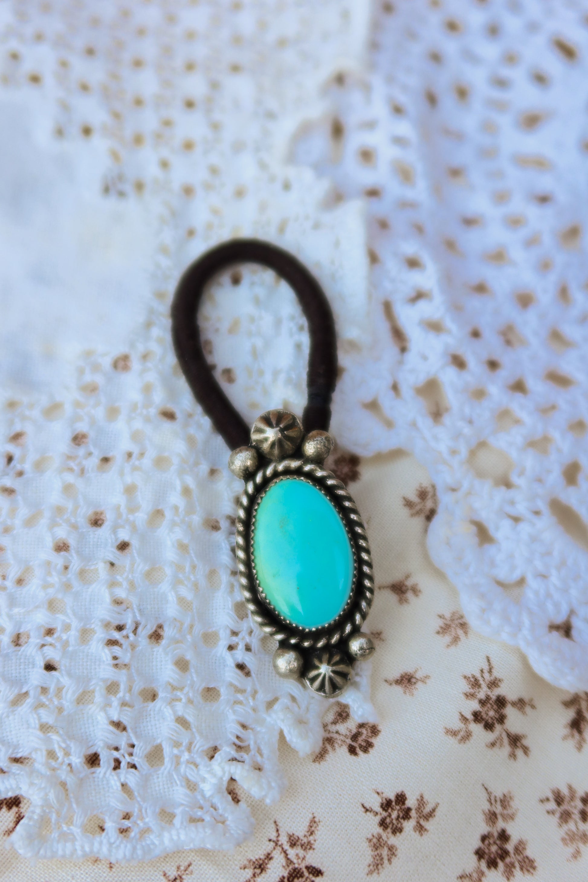 Elevate your everyday style with this stunning hair tie featuring genuine Sonoran turquoise with sterling silver ornaments. Available in three versatile options to match your look: Black, Brown, or blonde. Perfect for securing your hair while making a statement.&nbsp;