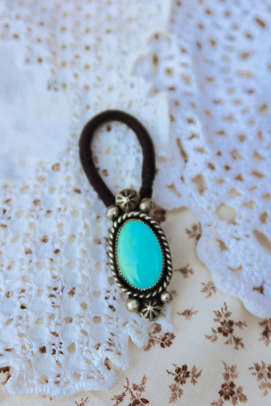 Elevate your everyday style with this stunning hair tie featuring genuine Sonoran turquoise with sterling silver ornaments. Available in three versatile options to match your look: Black, Brown, or blonde. Perfect for securing your hair while making a statement.&nbsp;
