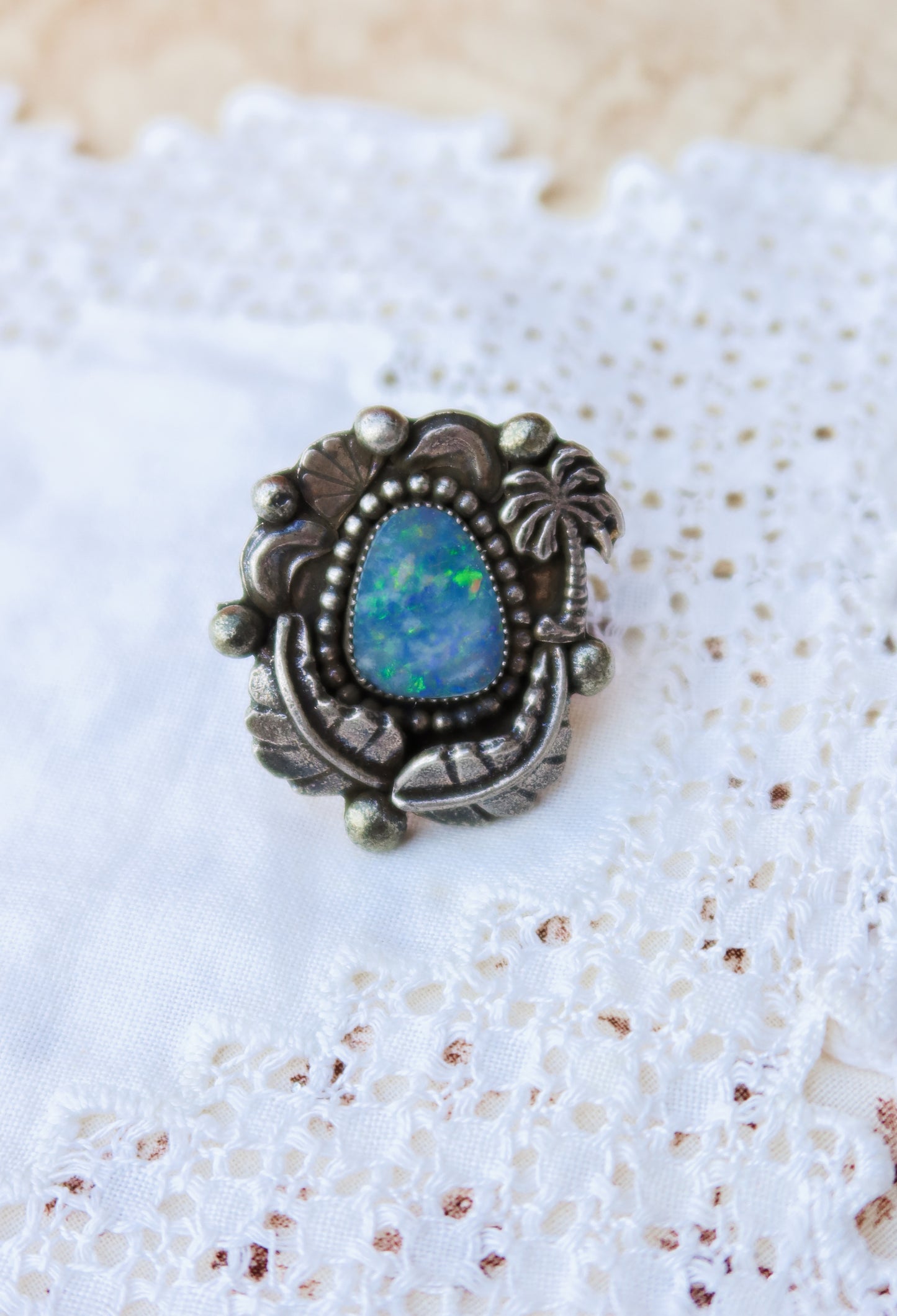 Sterling silver and genuine Australian opal ring size 7 1/2. Hand-crafted sand cast leaves and sand cast palm tree frame a luminous opal center. Perfect for those who want a coastal southwestern feel!