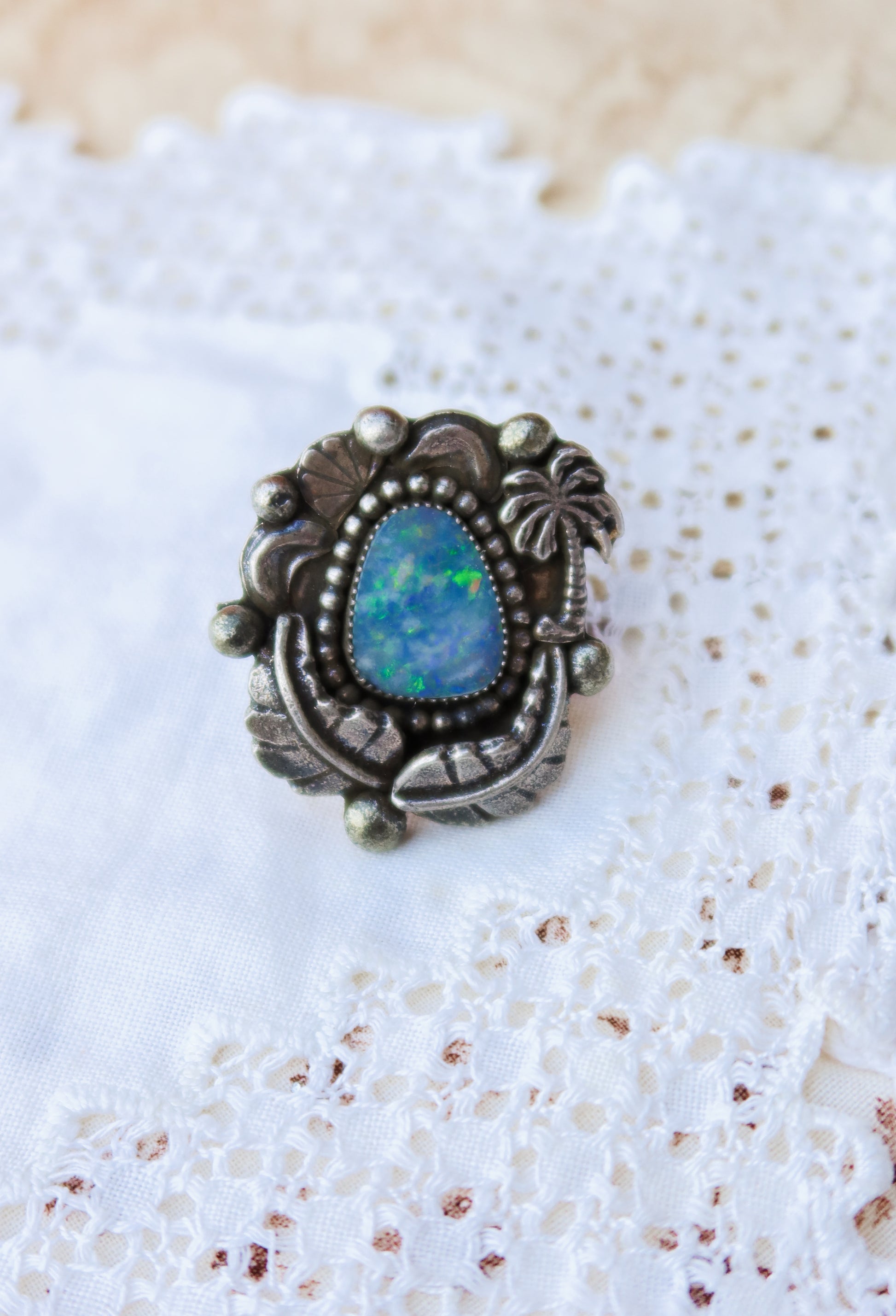 Sterling silver and genuine Australian opal ring size 7 1/2. Hand-crafted sand cast leaves and sand cast palm tree frame a luminous opal center. Perfect for those who want a coastal southwestern feel!