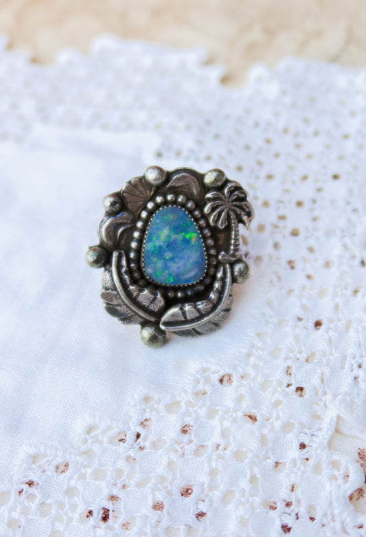 Sterling silver and genuine Australian opal ring size 7 1/2. Hand-crafted sand cast leaves and sand cast palm tree frame a luminous opal center. Perfect for those who want a coastal southwestern feel!