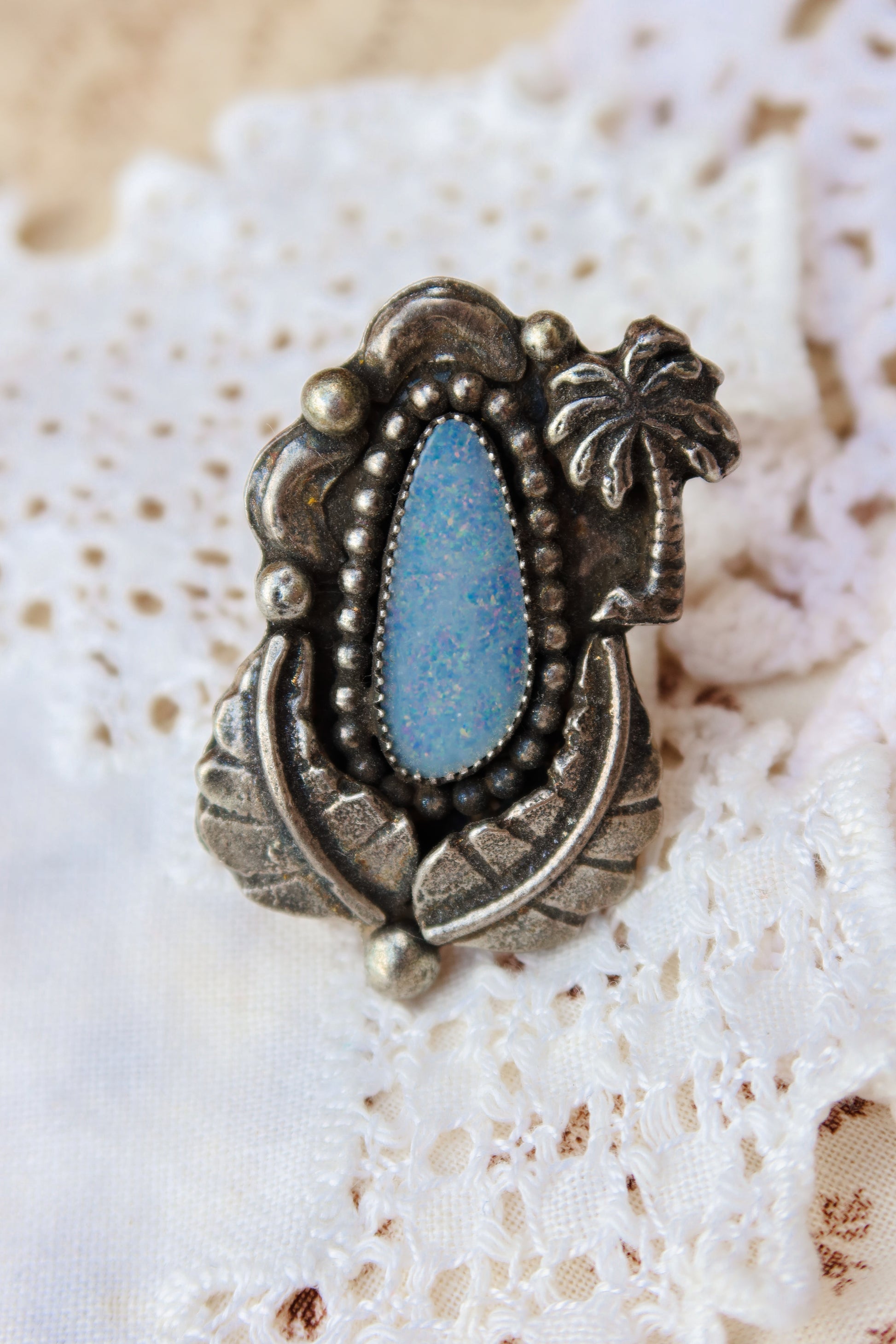 Sterling silver and genuine Australian opal ring size 9 1/2. Hand-crafted sand cast leaves and palm tree frame a luminous opal center. Perfect for those who want a coastal southwestern feel!