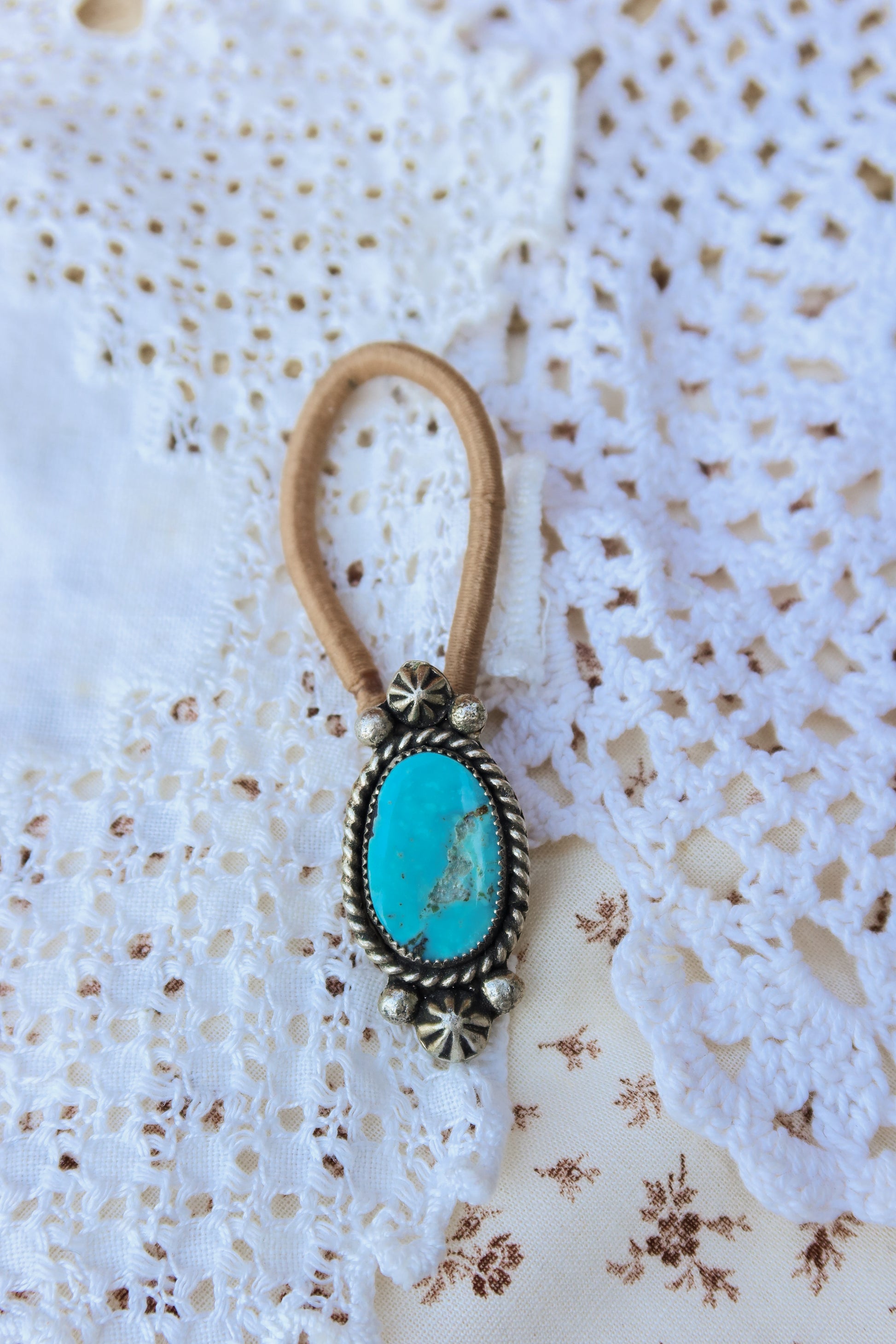 Elevate your everyday style with this stunning hair tie featuring genuine Sonoran turquoise with sterling silver ornaments. Available in three versatile options to match your look: Black, Brown, or blonde. Perfect for securing your hair while making a statement.
