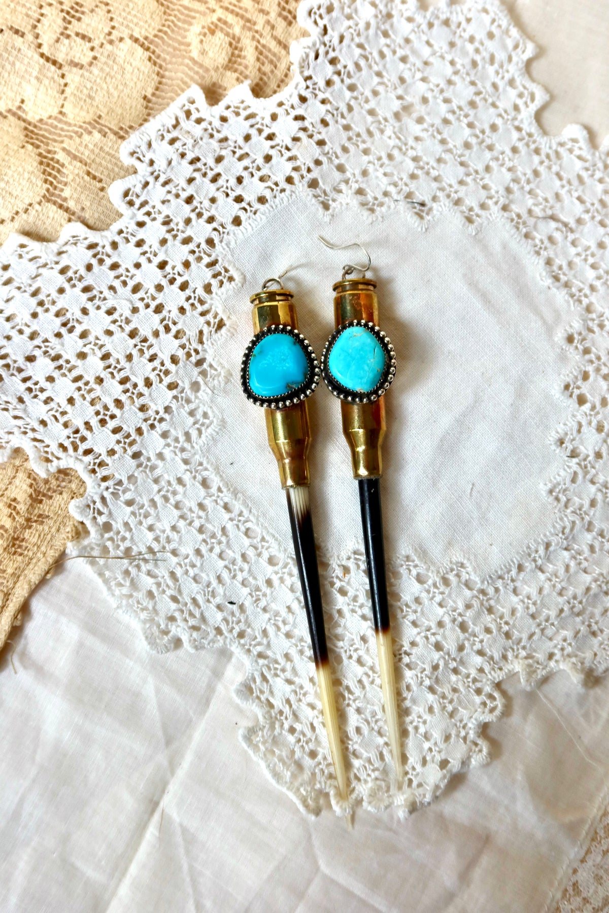These bold sterling silver earrings bring edge and elegance together. Featuring authentic bullet shells sourced by Jordan at a South Texas ranch, each pair combines raw history with refined craftsmanship. Turquoise and brass accents add warmth and color, while the sterling silver brings timeless shine.