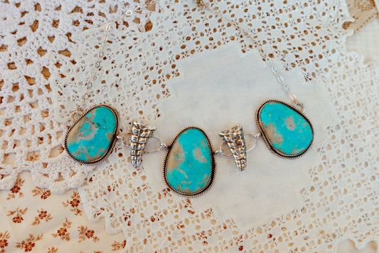 As seen on Ella Langley, shake things up with this whimsical Kingman Turquoise Sterling Silver Rattler choker—a bold statement piece that's equal parts charm and character. Handcrafted right here in South Texas, this beauty features stunning Kingman turquoise paired with sterling silver Rattlesnake rattlers sourced from South Texas. Whether you're channeling your inner whimsy or just love jewelry with personality, this rattler choker is the perfect conversation starter. Wear it proud and let your style shin