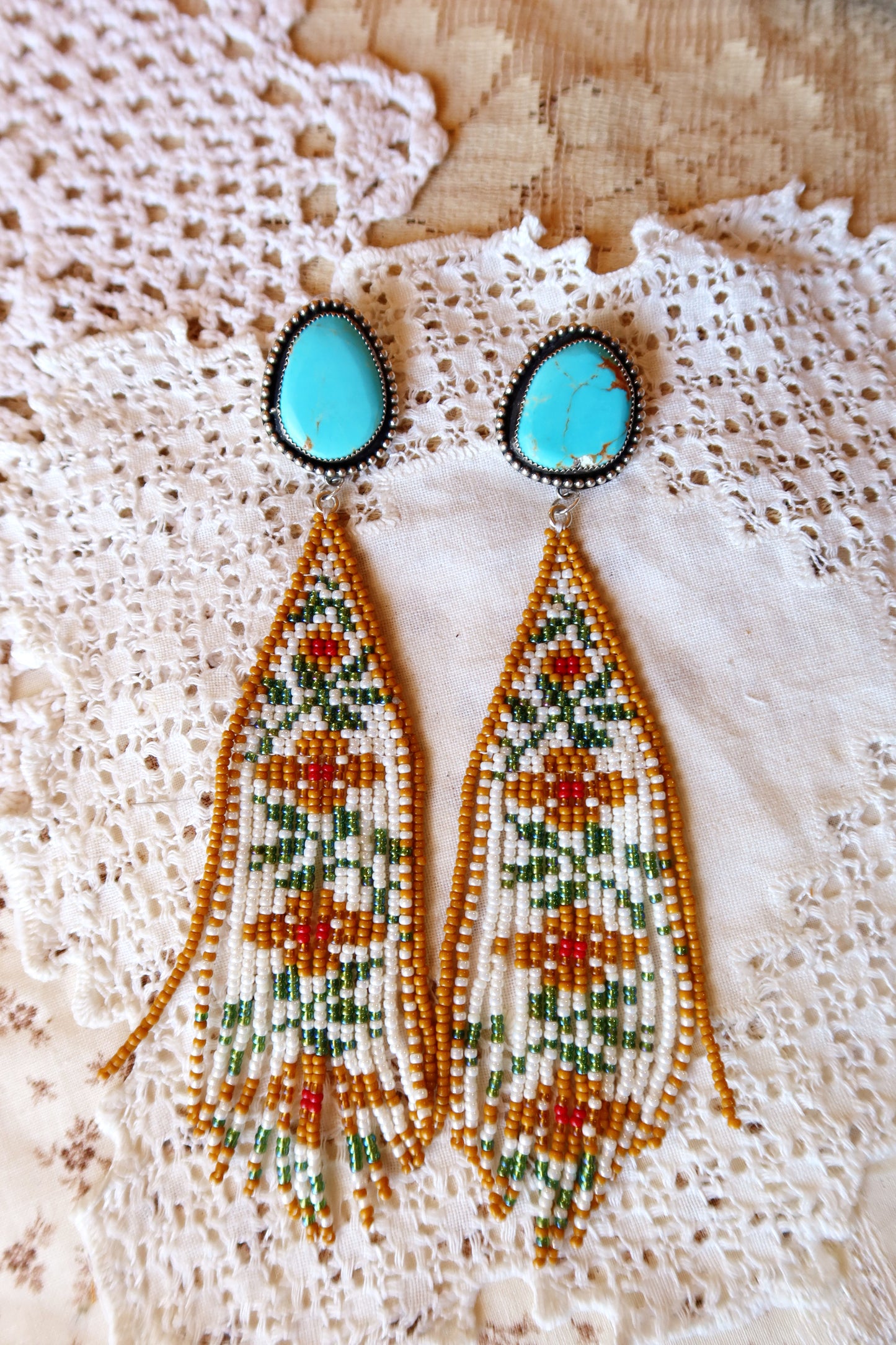 Bloom where you're beaded! These whimsical Sterling Silver and Turquoise Beaded Floral Earrings bring a touch of Southwestern charm to your everyday style. Each pair is meticulously hand-beaded with vibrant turquoise stones, creating delicate floral designs that dance with every movement. Handcrafted with love in South Texas, these earrings are a celebration of uniqueness and eccentric style. Perfect for adding a pop of color and personality to any outfit.