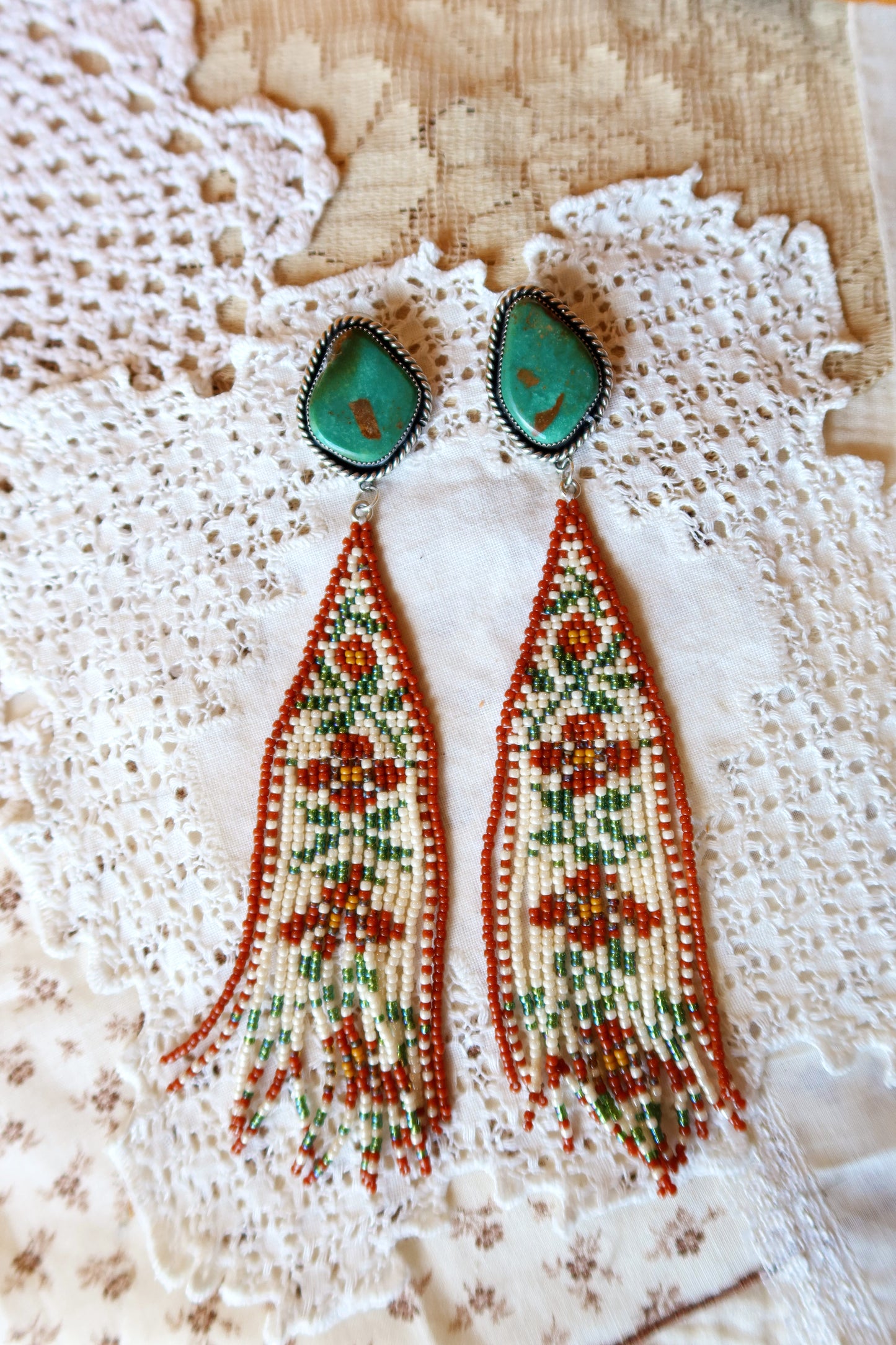 Bloom where you're beaded! These whimsical Sterling Silver and Turquoise Beaded Floral Earrings bring a touch of Southwestern charm to your everyday style. Each pair is meticulously hand-beaded with vibrant turquoise stones, creating delicate floral designs that dance with every movement. Handcrafted with love in South Texas, these earrings are a celebration of uniqueness and eccentric style. Perfect for adding a pop of color and personality to any outfit.