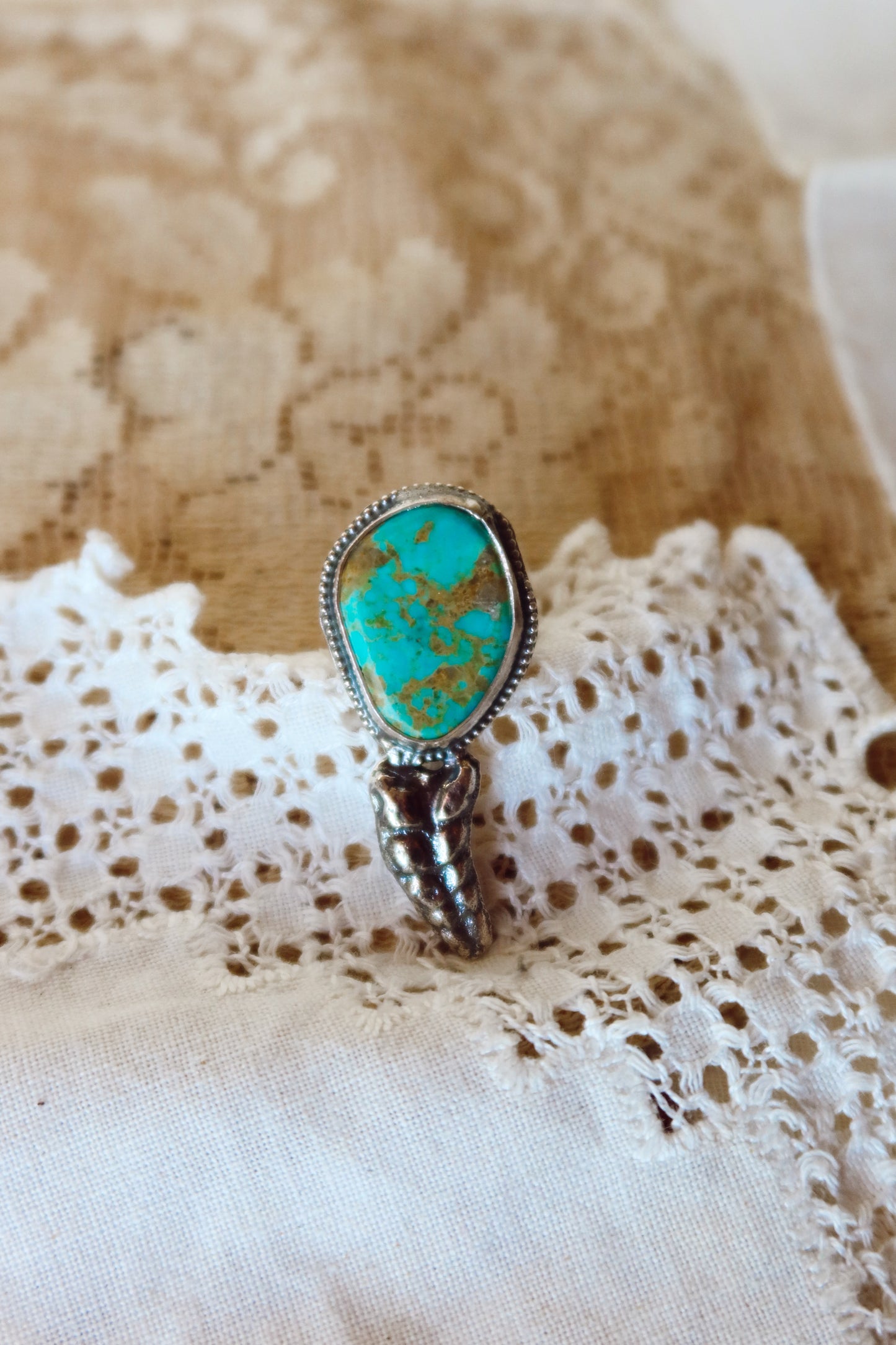  This one-of-a-kind Sterling Silver Kingman Turquoise Rattler Ring is handcrafted in the heart of South Texas. This whimsical beauty features a striking double ring shank design that wraps around your finger like a coiled serpent, crowned with genuine Kingman turquoise that captures the wild spirit of the south Texas Terrain. Each piece is uniquely crafted, making it a treasure that's as individual as you are.